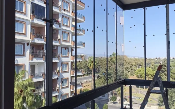 Cam balkonla kapatılmış köşe balkon, palmiye ve apartman manzarası