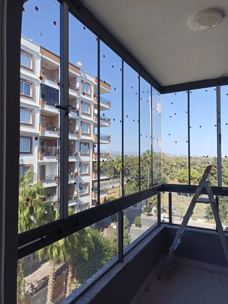 Cam balkonla kapatılmış köşe balkon, palmiye ve apartman manzarası