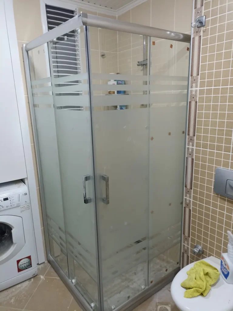 Çamaşır makinesinin yanına kurulmuş buzlu şeritli köşe duşakabin