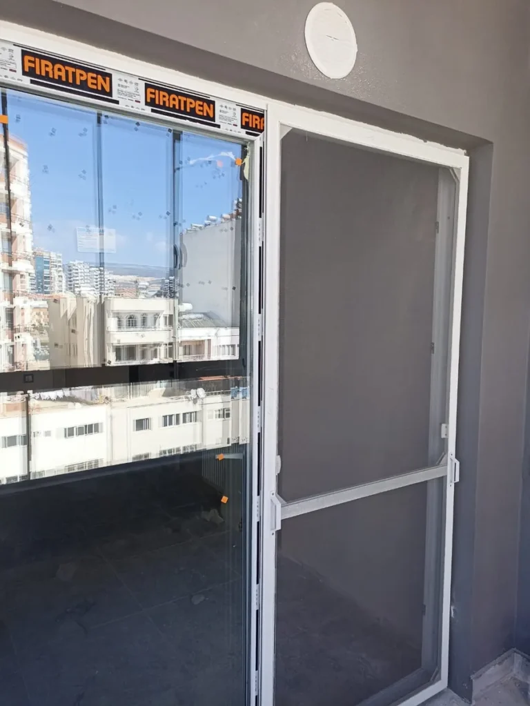 Koruyucu bandıyla yeni PVC balkon kapısı ve yanında beyaz çerçeveli sineklik