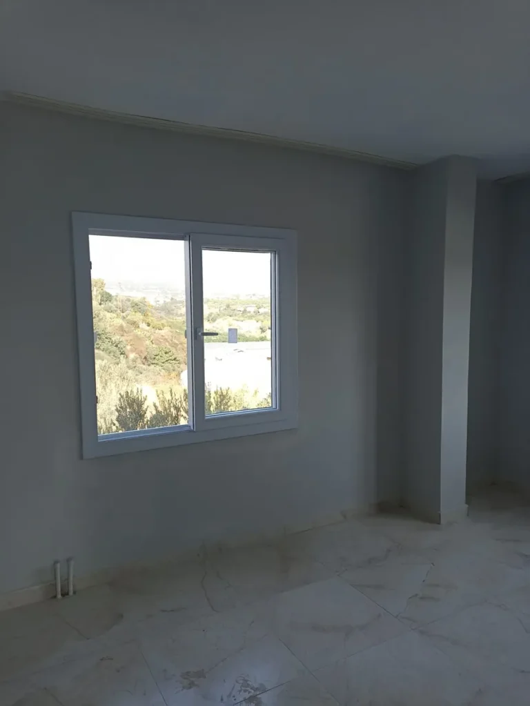 Boş odada iki kanatlı beyaz PVC pencere montajı